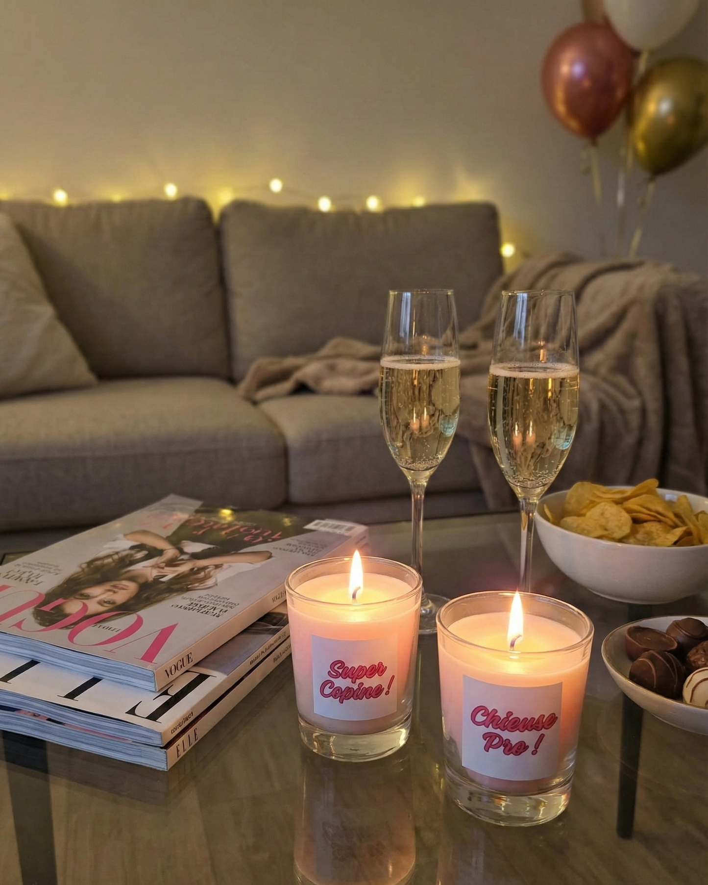 Bougies cadeaux "Super Copine" et "Chieuse Pro" sur une table basse avec champagne, magazines et chocolats pour une soirée cocooning entre amies