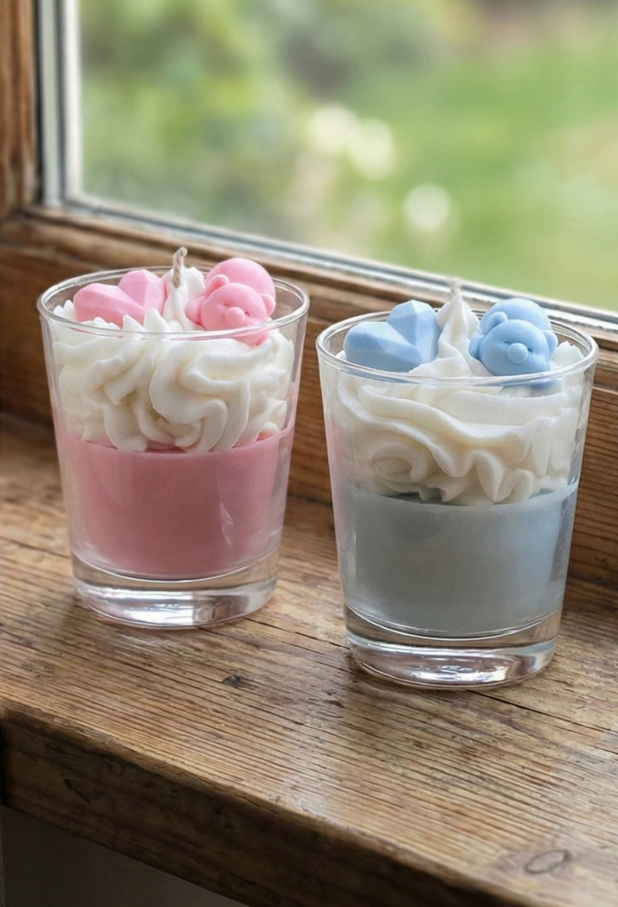 Duo de bougies gourmandes chantilly rose et bleue avec oursons sur un rebord de fenêtre en bois, lumière naturelle