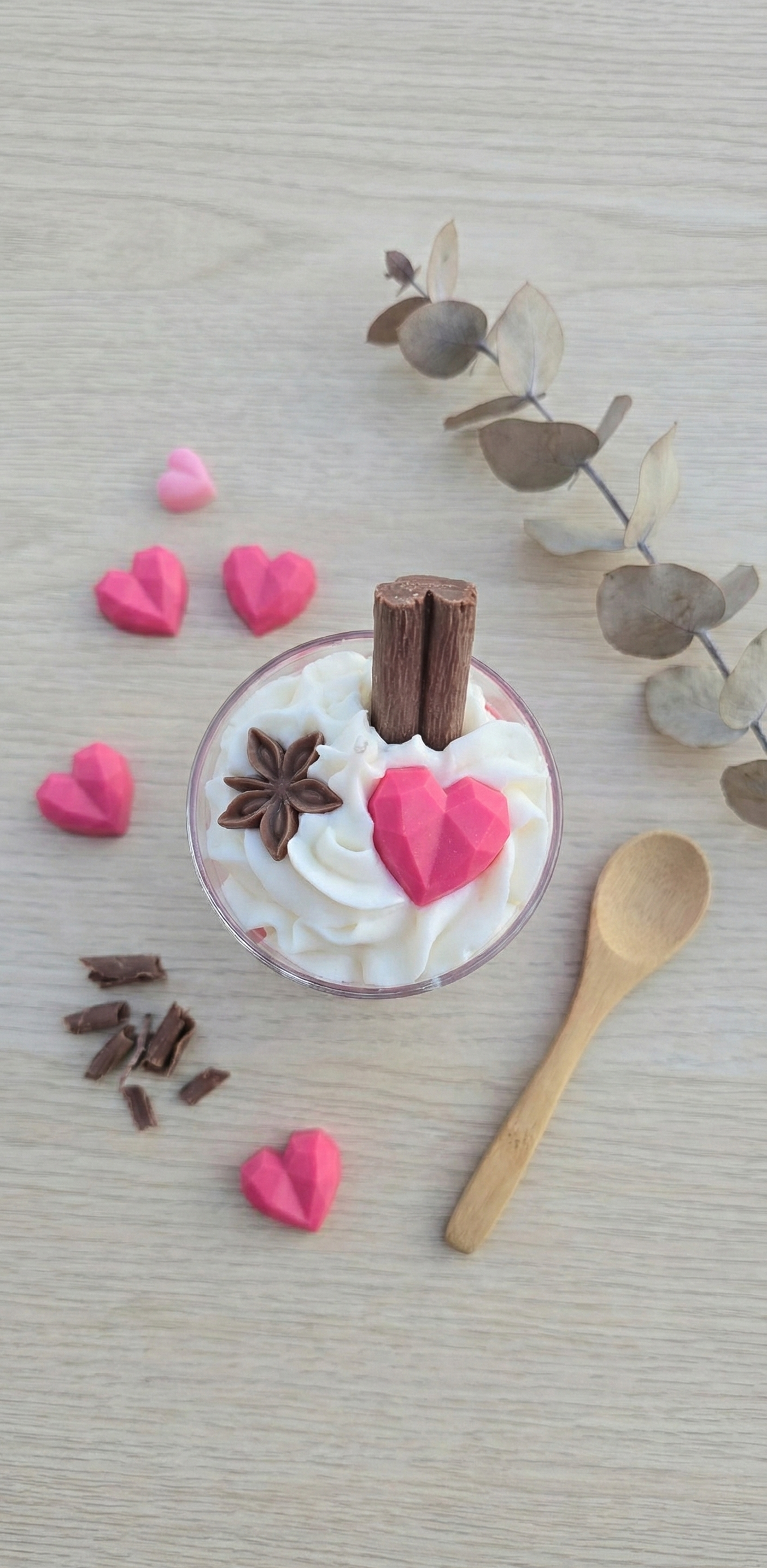 Vue de dessus d'une bougie chantilly avec décorations en cire cœur et chocolat, disposée sur une table en bois avec accessoires